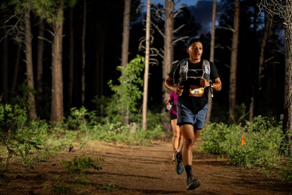 A runner with headlamp on the forest trail