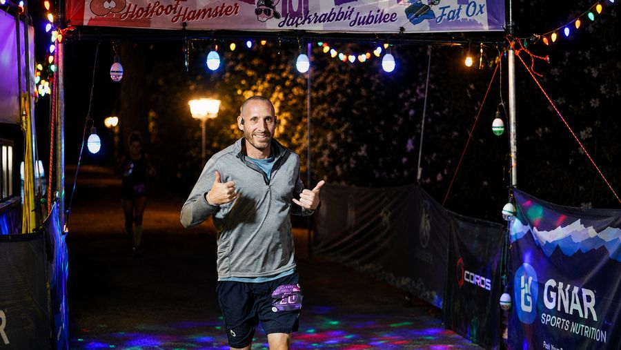 A runner at the lit-up finish arch at night