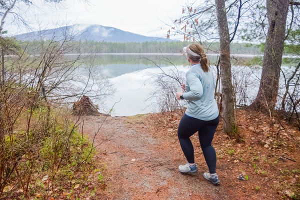A runner on the shore path above the still lake