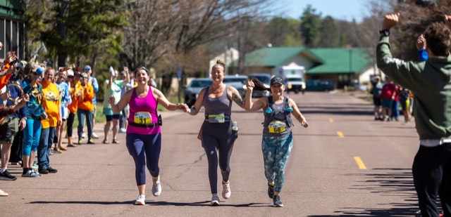 Three finishers holding hands down the finishing stretch