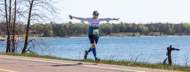 A runner with arms spread wide beside the lake